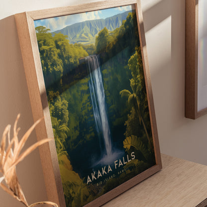 A framed poster of Akaka Falls is displayed on a wooden surface, showcasing a waterfall surrounded by lush greenery and distant mountains under a blue sky.