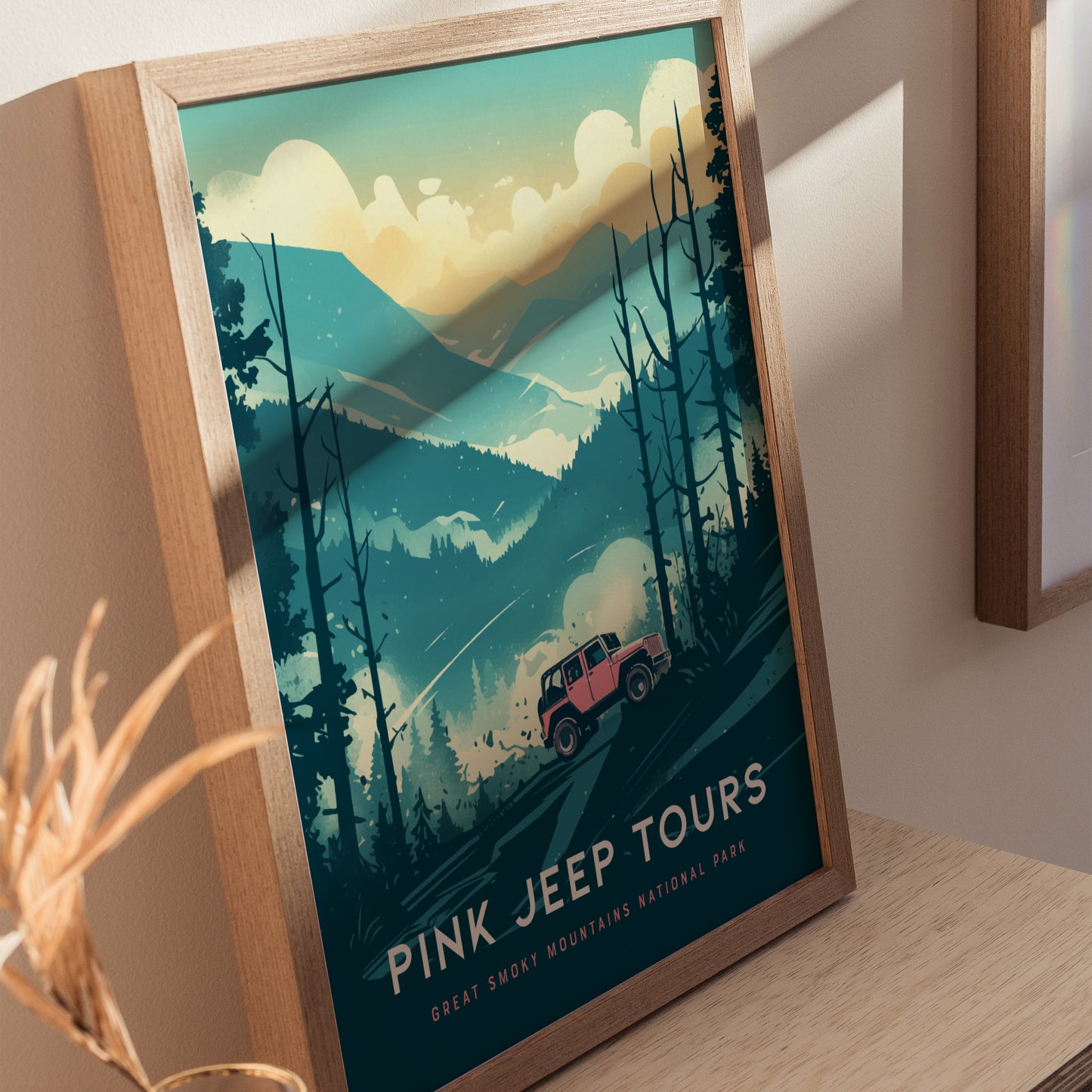 A framed poster depicts a pink jeep navigating through a stylized, misty landscape of the Great Smoky Mountains, surrounded by trees and mountains under a cloudy sky. The text reads Pink Jeep Tours, Great Smoky Mountains National Park.