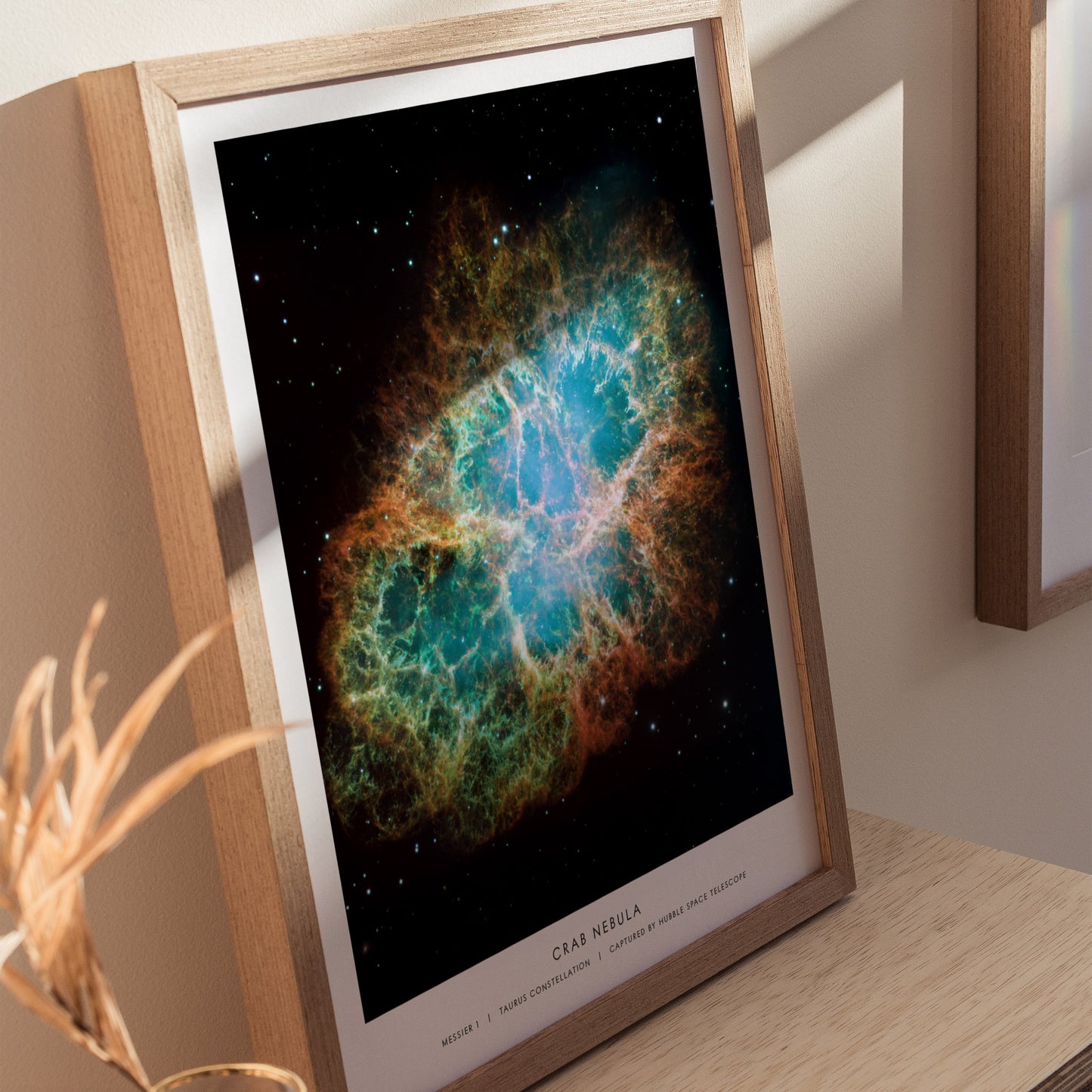 Framed poster of the Crab Nebula on a wooden surface with a neutral background