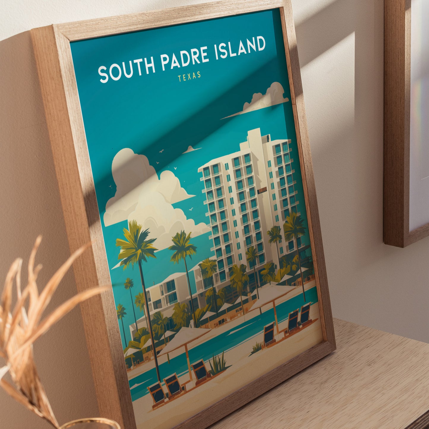 Framed South Padre Island poster featuring a modern beachside hotel, palm trees, and lounge chairs under umbrellas. The artwork has a vibrant blue sky and tropical ambiance.
