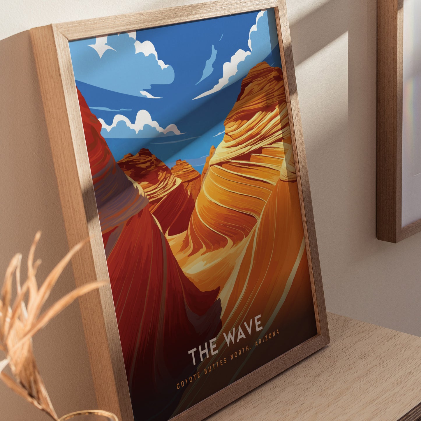 Framed poster featuring vibrant, swirling sandstone formations under a blue sky with clouds, labeled The Wave Coyote Buttes North, Arizona, displayed on a wooden surface.
