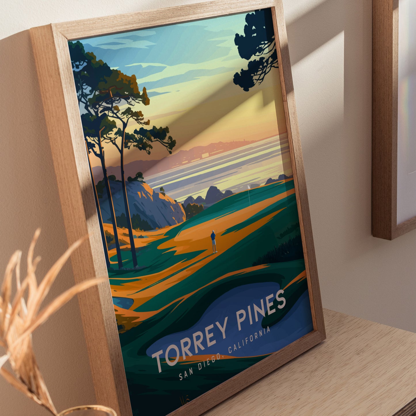 Framed poster of Torrey Pines Golf Course featuring vibrant coastal cliffs, trees, and a figure on a fairway at sunset. Text reads Torrey Pines, San Diego, California.