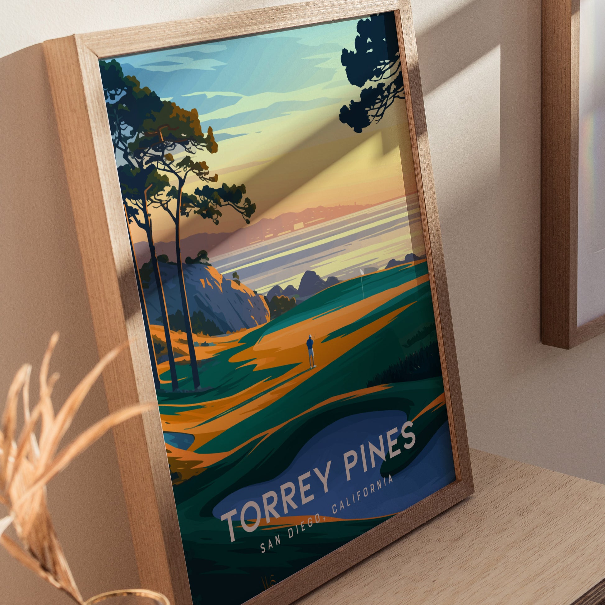 Framed poster of Torrey Pines Golf Course featuring vibrant coastal cliffs, trees, and a figure on a fairway at sunset. Text reads Torrey Pines, San Diego, California.