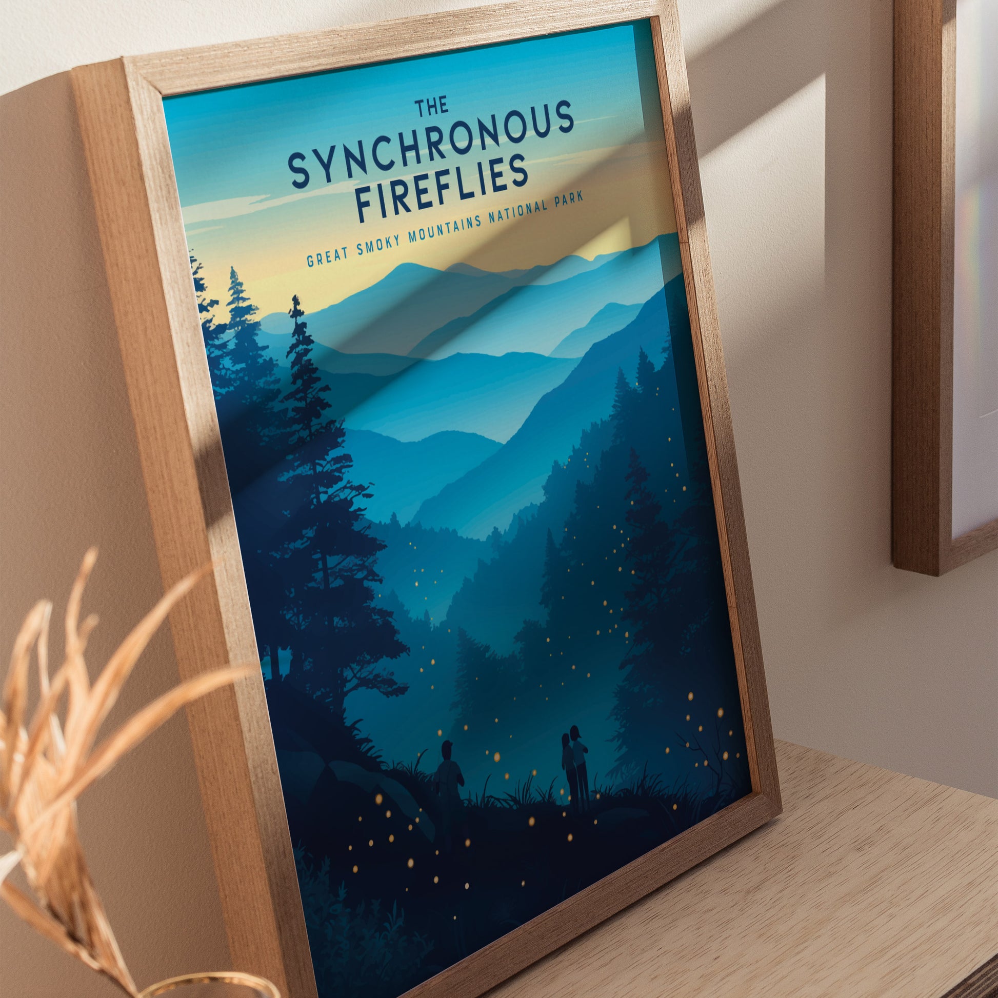 A framed poster titled The Synchronous Fireflies depicts a serene mountain landscape with silhouettes of trees and small glowing fireflies. The artwork captures a magical evening in the Great Smoky Mountains National Park.