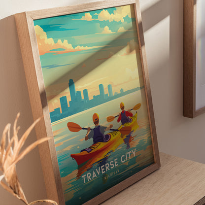 A framed Traverse City poster shows two kayakers paddling on serene water, with a city skyline and colorful sky in the background. The artwork captures a peaceful outdoor scene.