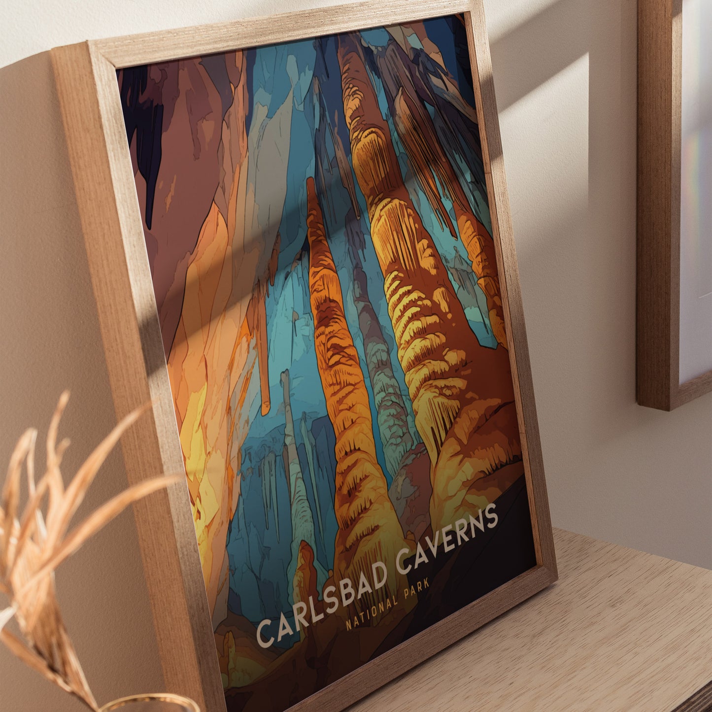 Framed Carlsbad Caverns National Park poster showcasing vibrant rock formations in blue, orange, and yellow hues, placed on a wooden surface with natural lighting.