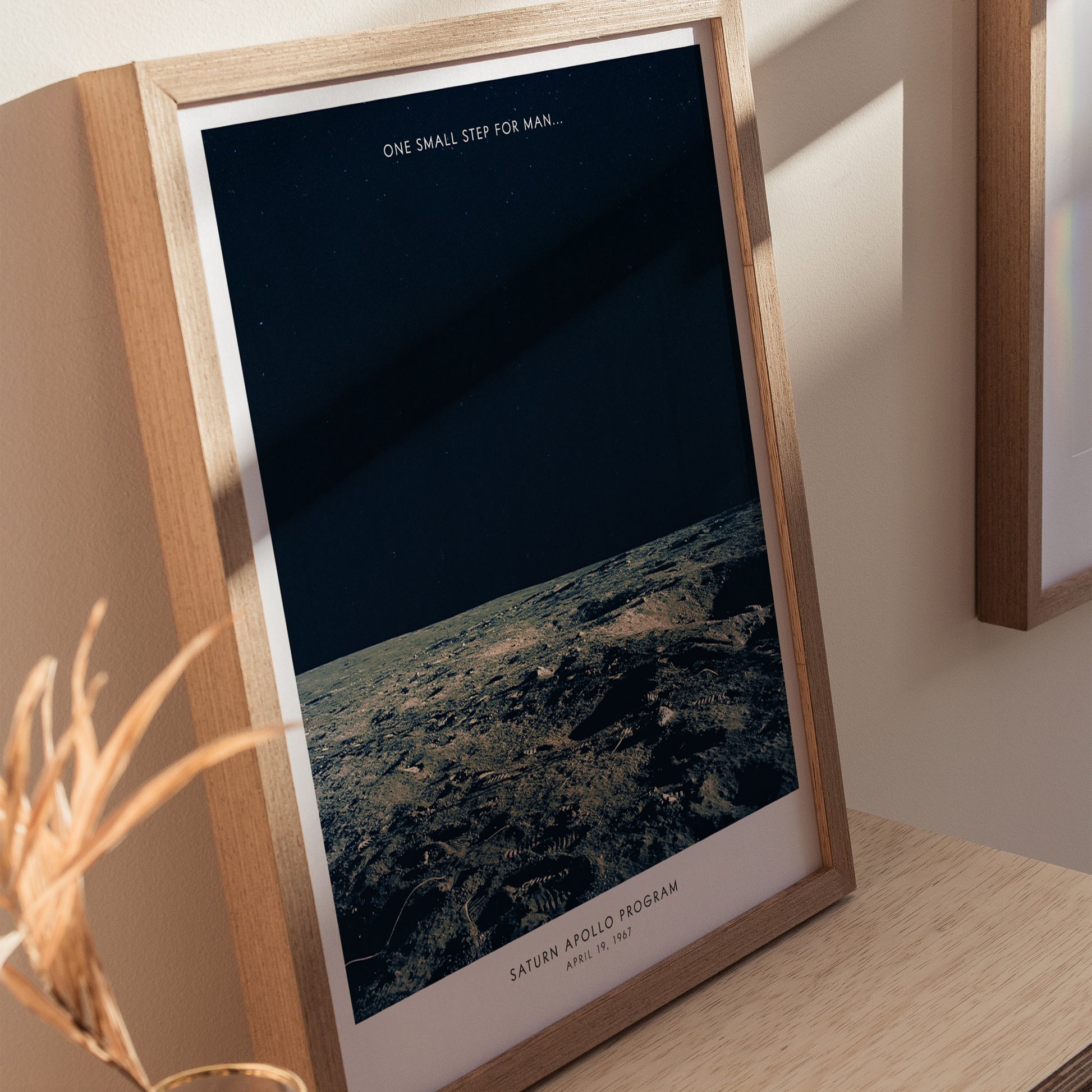 Framed Apollo 12 Moon Landing poster centered on a white wall with minimalist decor