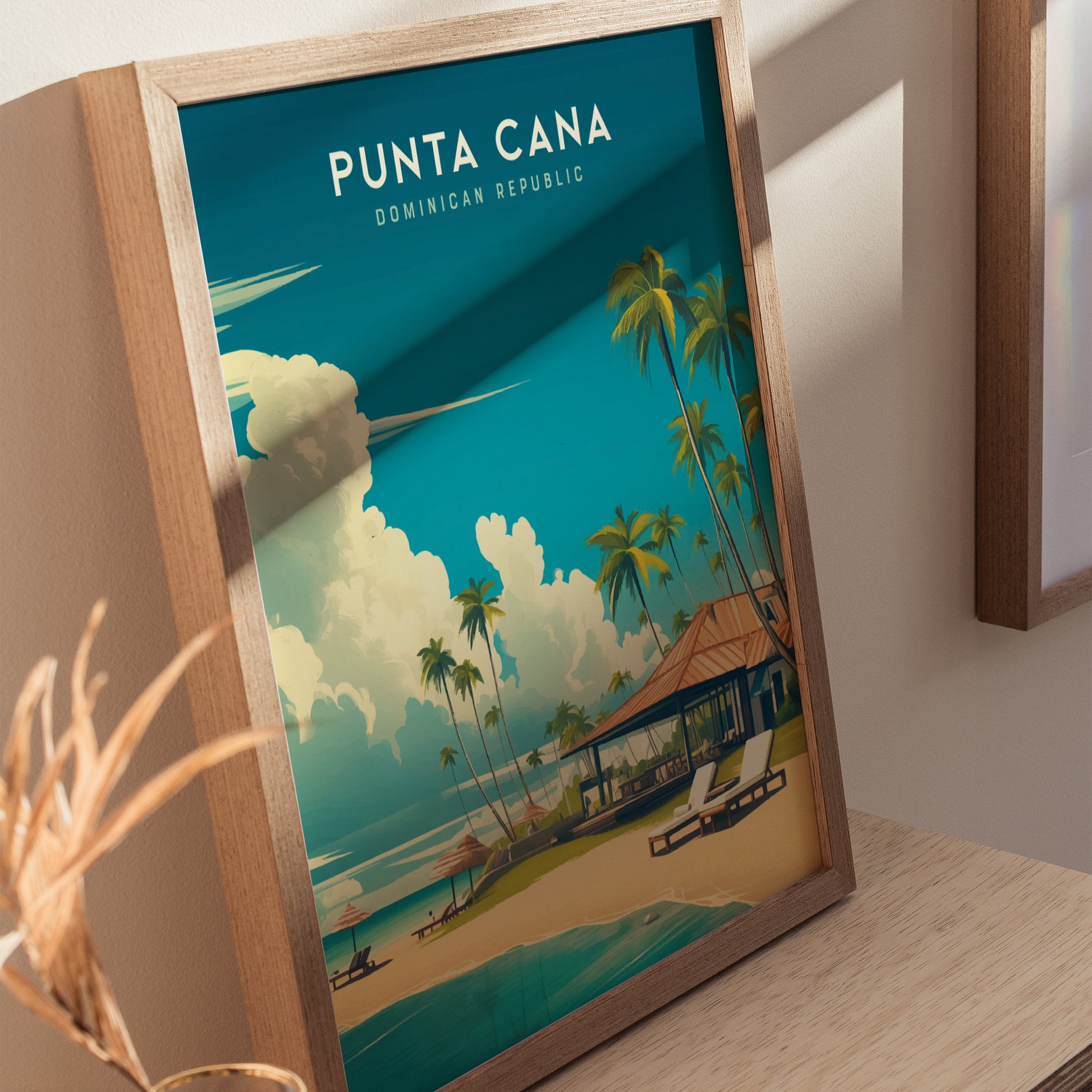 A framed Punta Cana poster features a vibrant illustration of a tropical beach scene with palm trees, a sandy shore, and a blue sky with fluffy clouds. The poster is set against a light-colored wall, adding a touch of Caribbean charm.