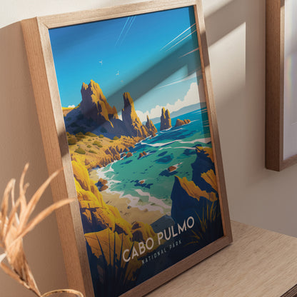 Framed art print depicting a vibrant coastal landscape with rocky cliffs, turquoise waters, and clear blue skies, labeled Cabo Pulmo National Park. Shadows and light create a warm atmosphere.