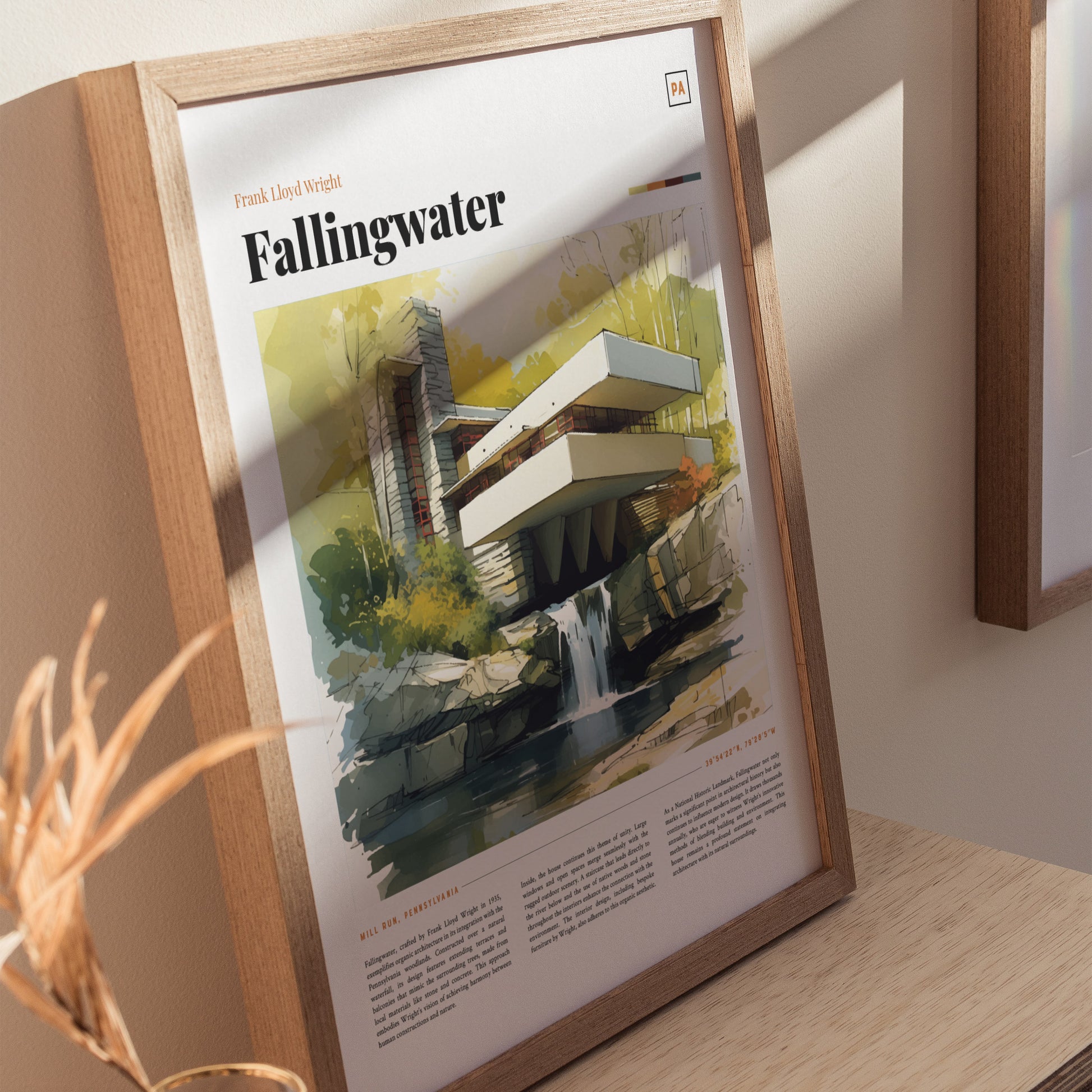 A framed poster of Frank Lloyd Wrights Fallingwater, showcasing a watercolor illustration of the iconic house surrounded by nature, is displayed on a wooden surface.