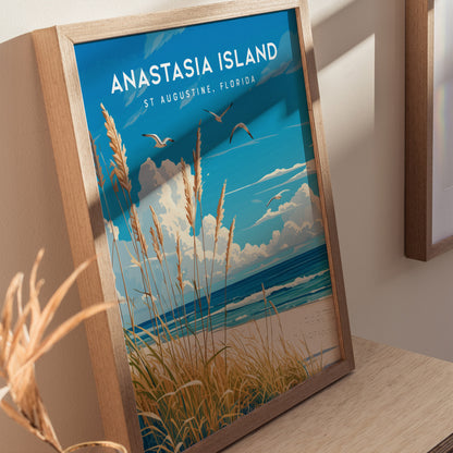 A framed poster of Anastasia Island in St. Augustine, Florida, featuring sea oats, a blue sky, and seabirds over the ocean. Its displayed on a wooden surface.