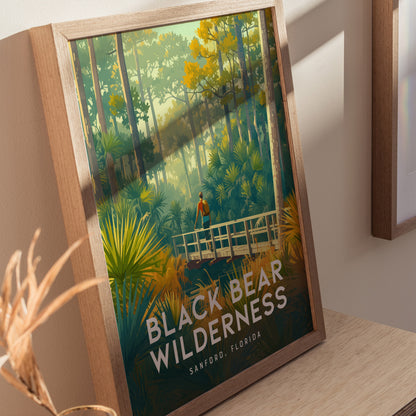 Framed poster of Black Bear Wilderness in Sanford, Florida, depicting a hiker on a wooden bridge surrounded by lush greenery and towering trees. Sunlight filters through the forest canopy.