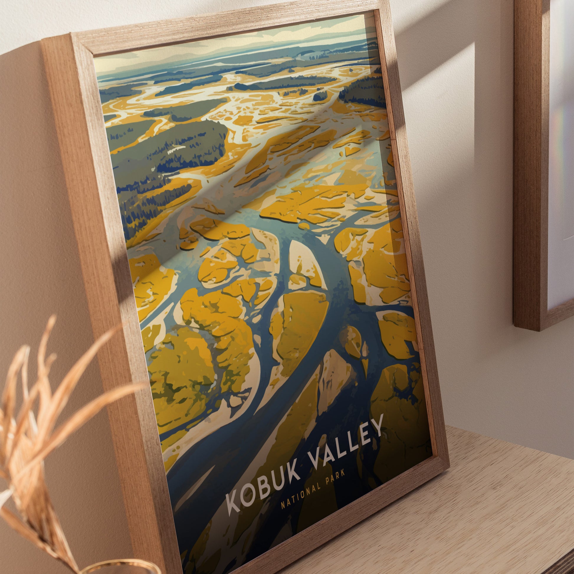 Framed poster of Kobuk Valley National Park on a wooden surface, depicting abstract yellow and blue patterns resembling a landscape.