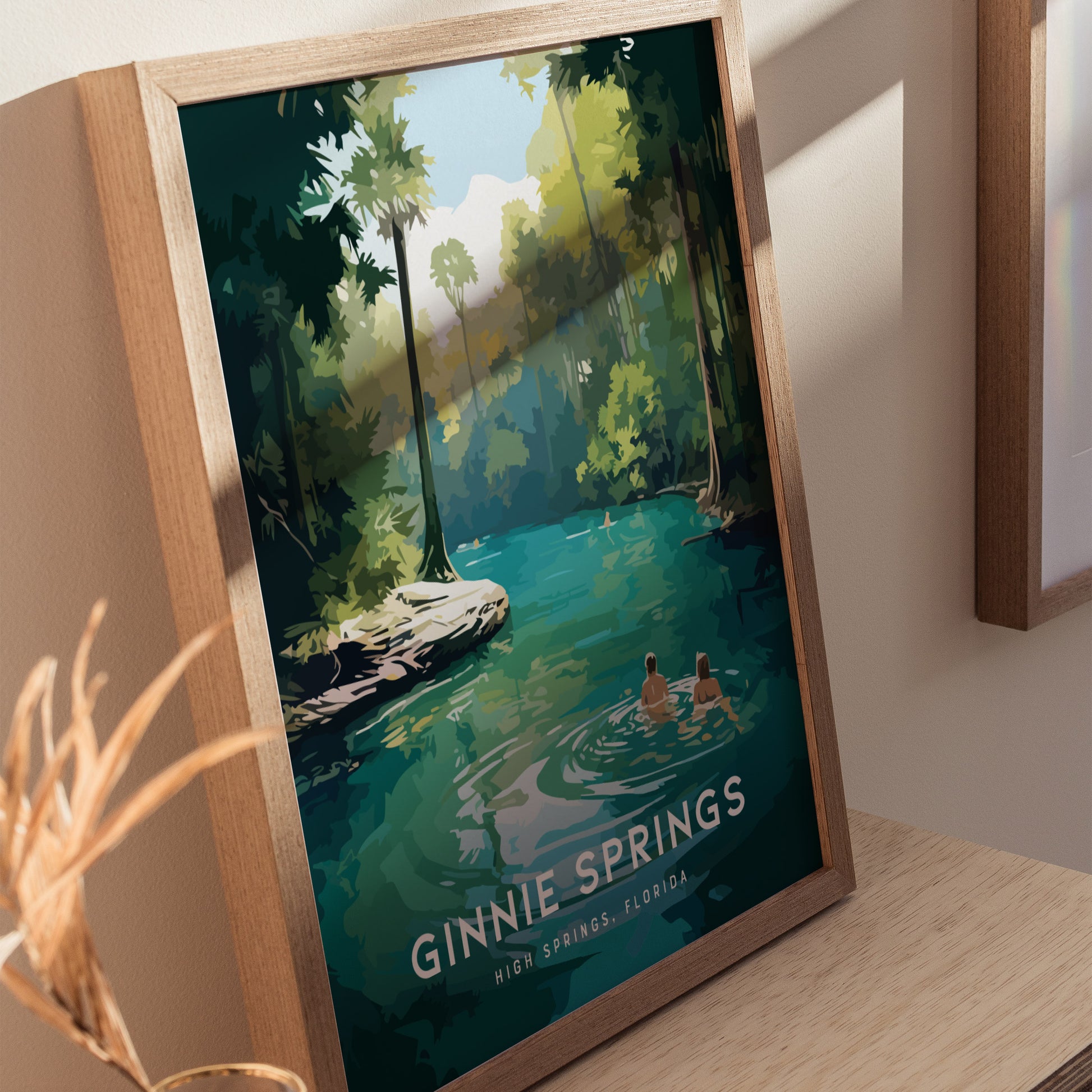 Framed artwork of Ginnie Springs, Florida, depicting two people wading in turquoise waters under lush green trees. Natural light casts shadows, enhancing the serene atmosphere.