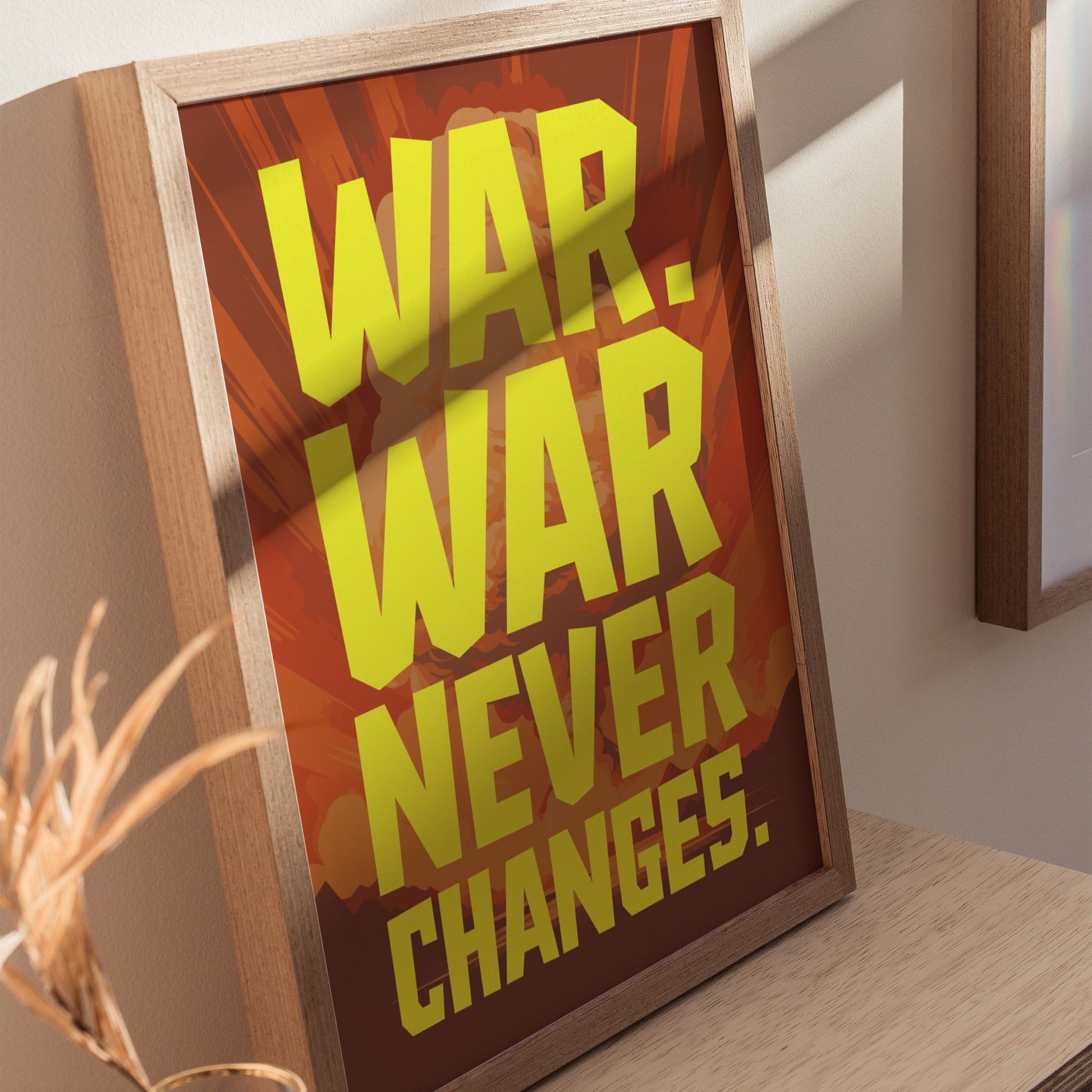 A framed poster with bold yellow text reading WAR. WAR NEVER CHANGES. on a red and orange background, leaning against a light-colored wall.