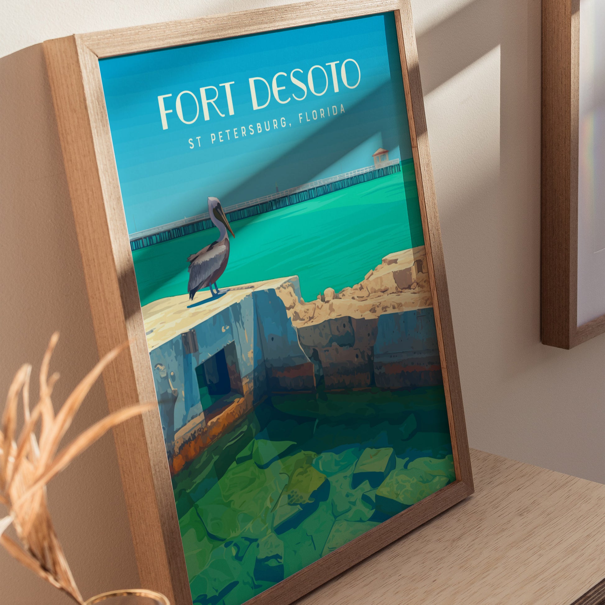 A framed poster of Fort Desoto in St. Petersburg, Florida, featuring a pelican on weathered fort ruins with turquoise waters and a distant pier.