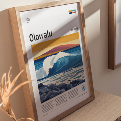 Framed poster of Olowalu, Maui, featuring vibrant waves and a colorful sunset, displayed on a wooden surface with soft shadows. Text and graphics enhance the coastal theme.