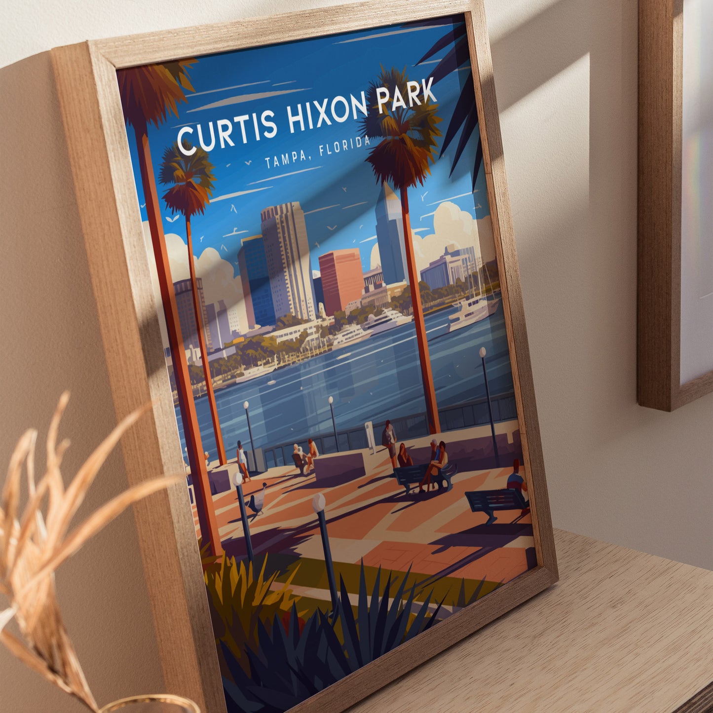 Framed artwork of Curtis Hixon Park in Tampa, Florida, featuring people walking along a riverside promenade with palm trees, city skyline, and boats on the water under a blue sky.