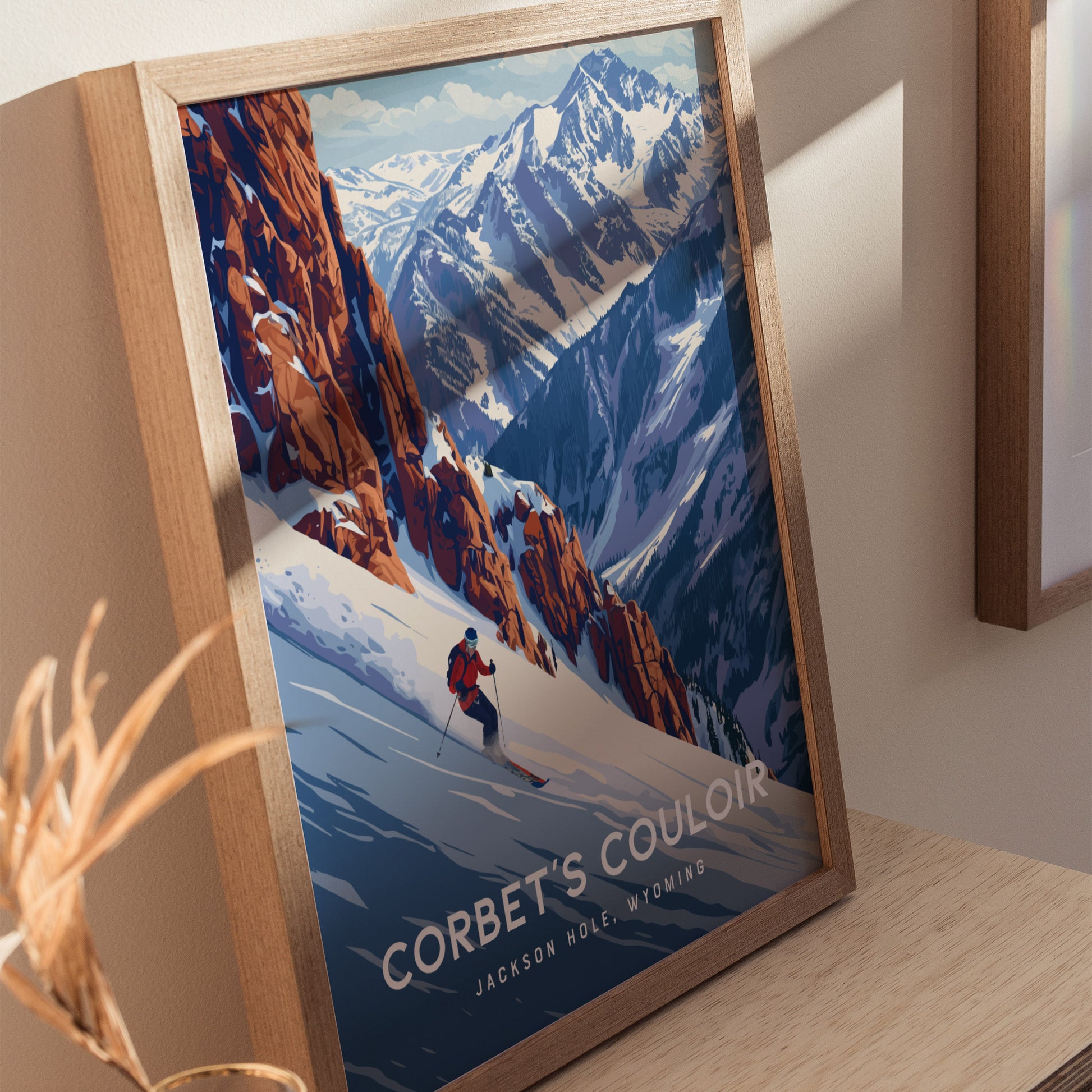 A framed poster depicts a skier descending a steep snow-covered slope with rugged mountains in the background, titled Corbets Couloir, Jackson Hole.
