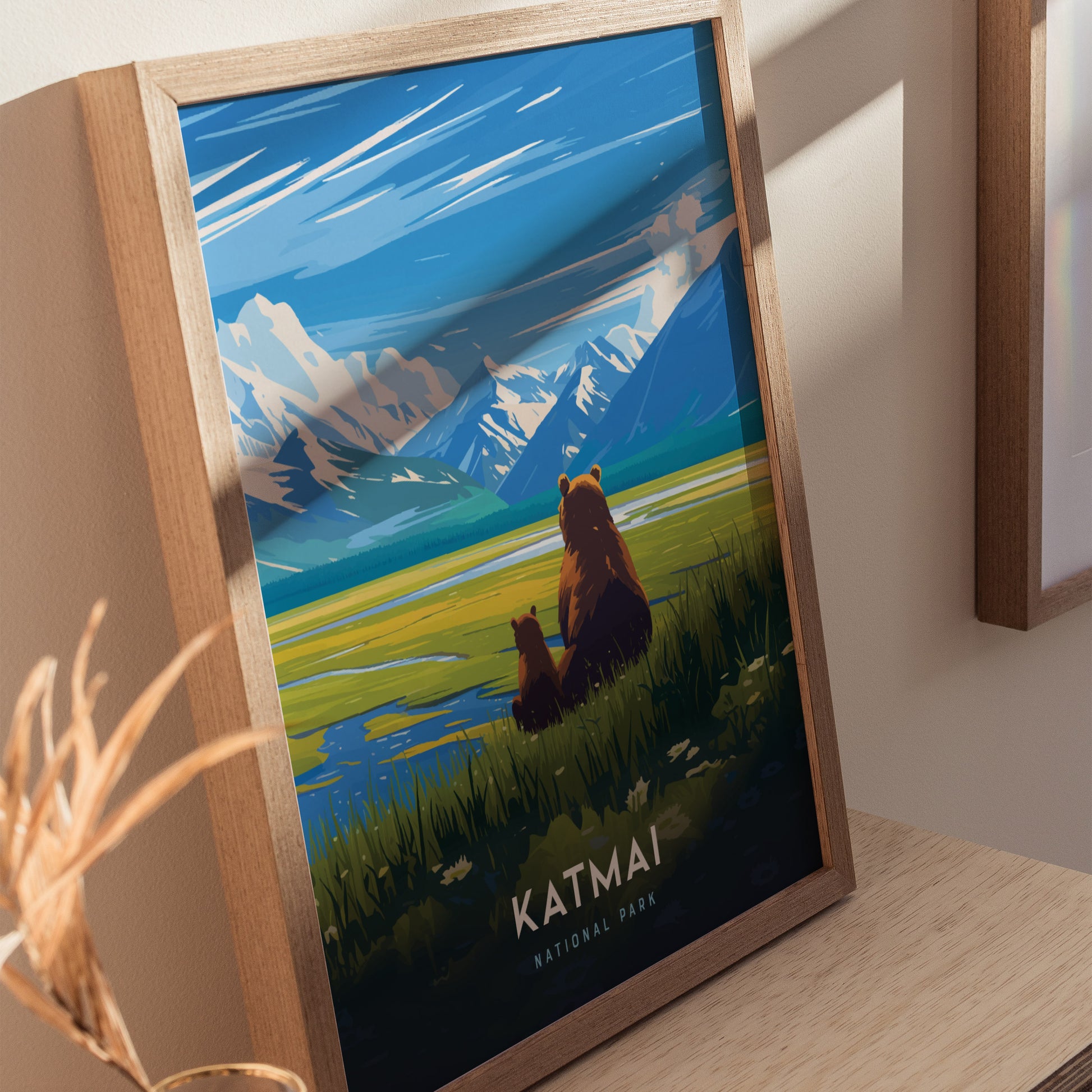 Framed poster depicting two brown bears sitting by a lake, with snow-capped mountains and a vibrant sky in the background. The poster is titled Katmai National Park.