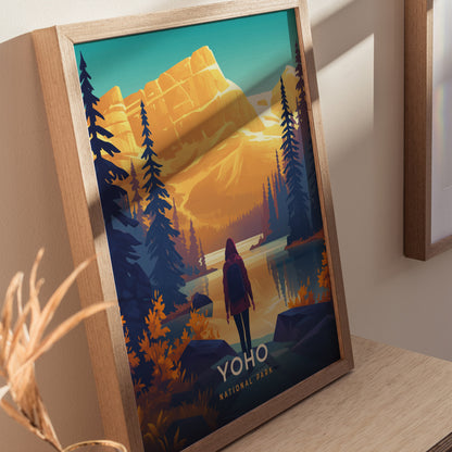 A framed poster features a stylized illustration of Yoho National Park with a hiker, towering trees, and majestic mountains under a vibrant sky. The text reads Yoho National Park.
