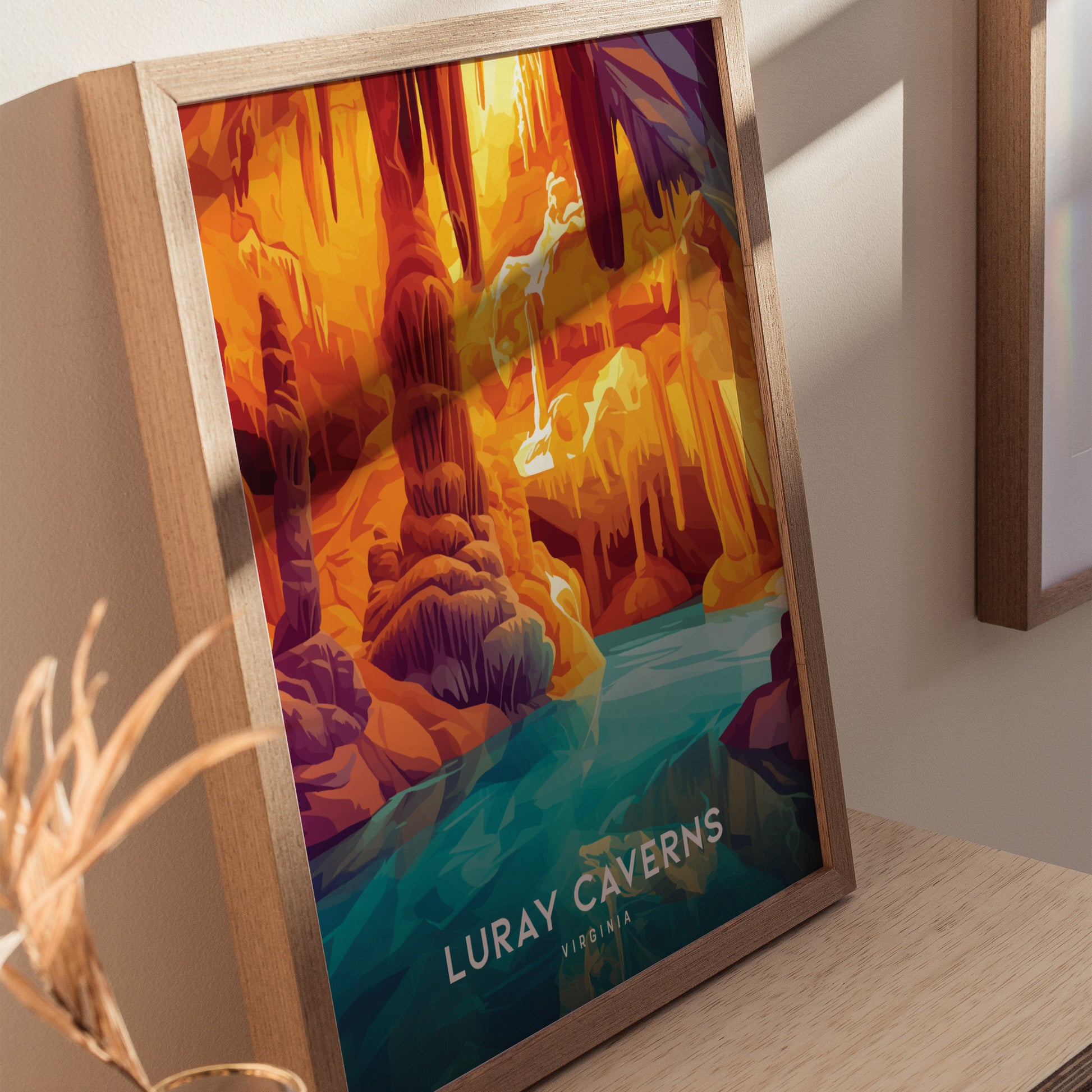 Framed poster of Luray Caverns in vivid colors, depicting intricate stalactites and a reflective pool, leaning against a light wall on a wooden surface.