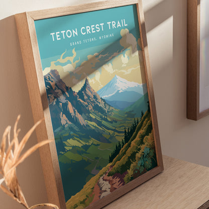 Framed poster of the Teton Crest Trail featuring colorful mountains and valleys under a cloudy sky, displayed on a light wooden surface.
