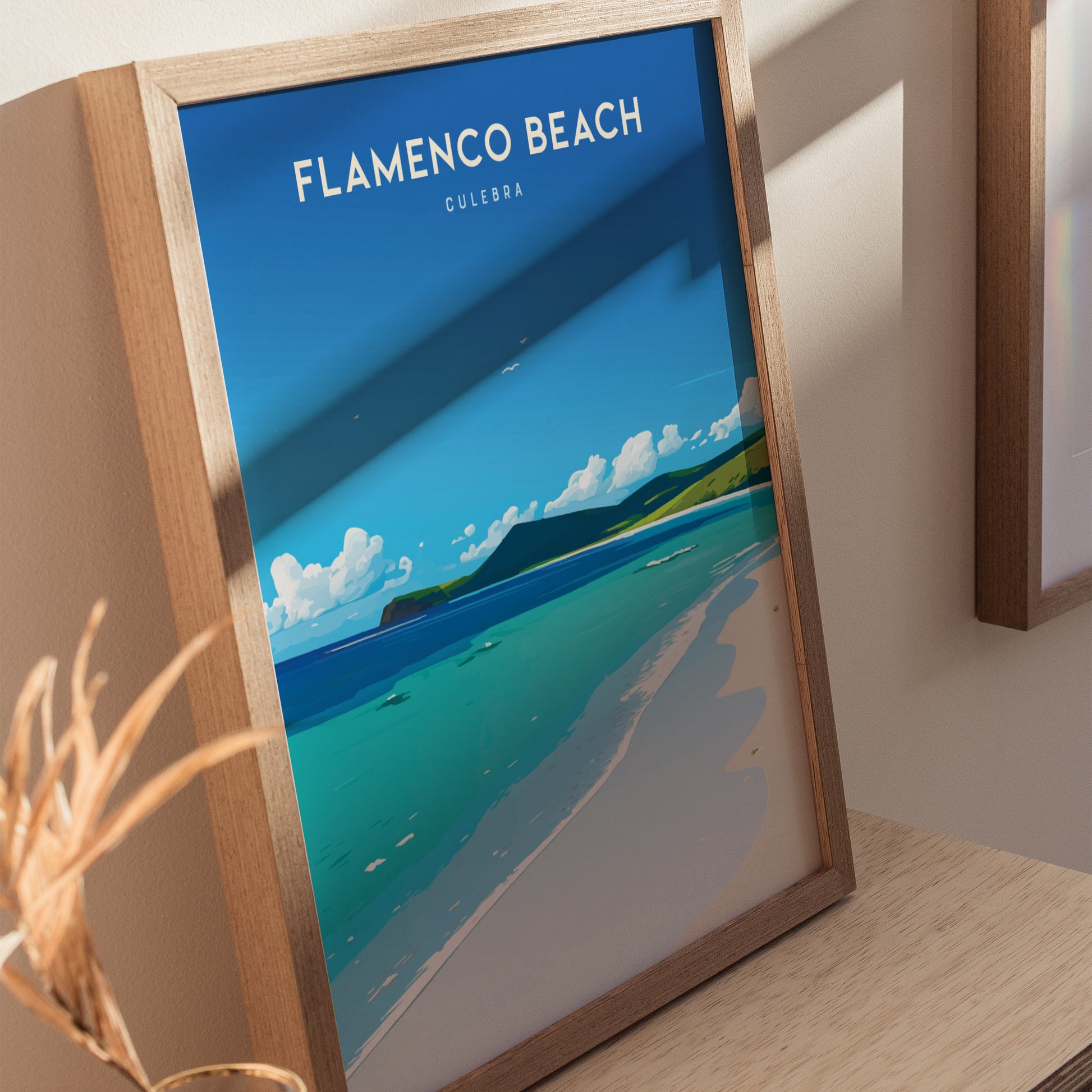 A framed poster of Flamenco Beach, Culebra, Puerto Rico, showcasing vibrant turquoise waters, white sands, and a clear blue sky, leaning against a light-colored wall.
