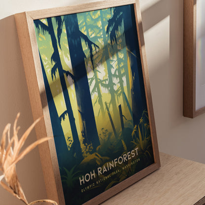 Framed artwork of the Hoh Rainforest features stylized trees and foliage in vibrant green and blue tones. The wooden frame rests on a light wooden surface, casting soft shadows.