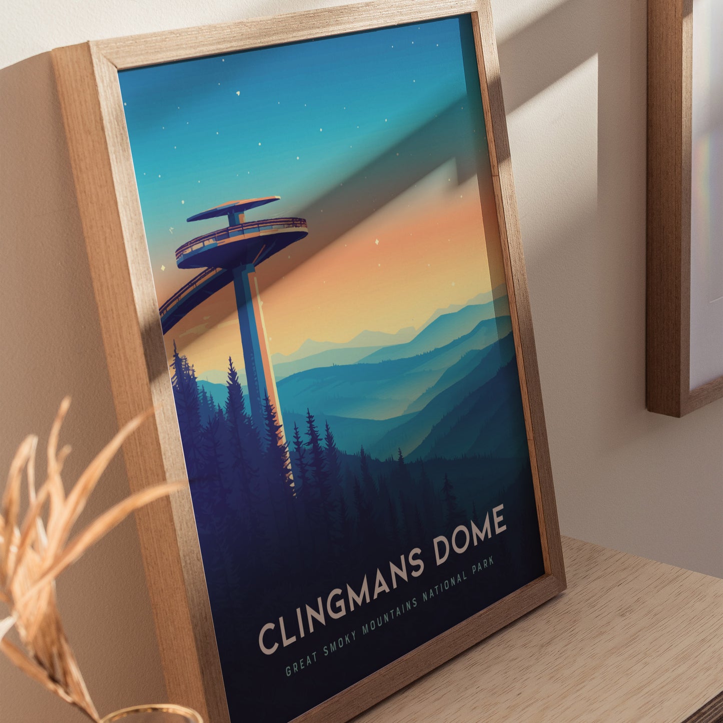 A framed poster of Clingmans Dome with an artistic depiction of the observation tower and layered mountain ridges at sunset. The vibrant colors transition from orange to blue, capturing the serene beauty of the Great Smoky Mountains.