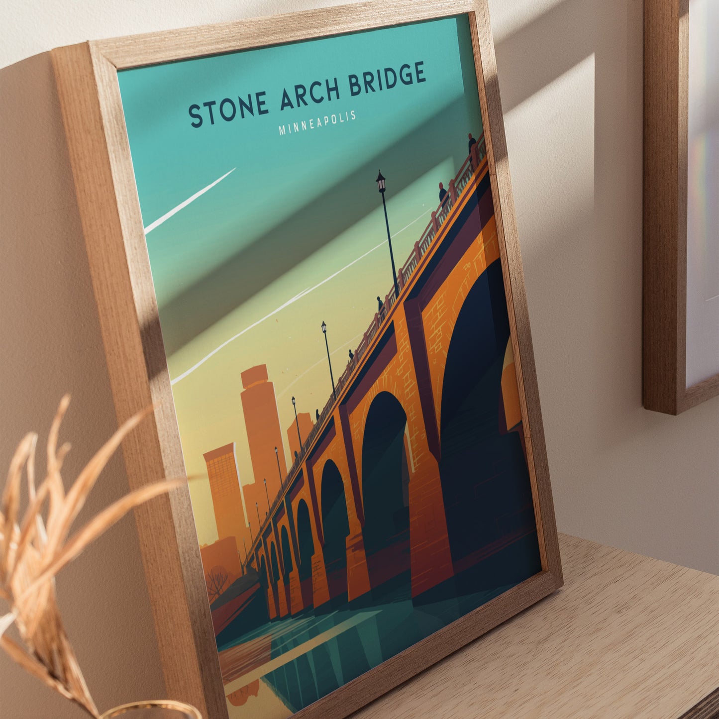 Framed poster depicting the Stone Arch Bridge in Minneapolis, with an orange and blue color scheme and the city skyline in the background.
