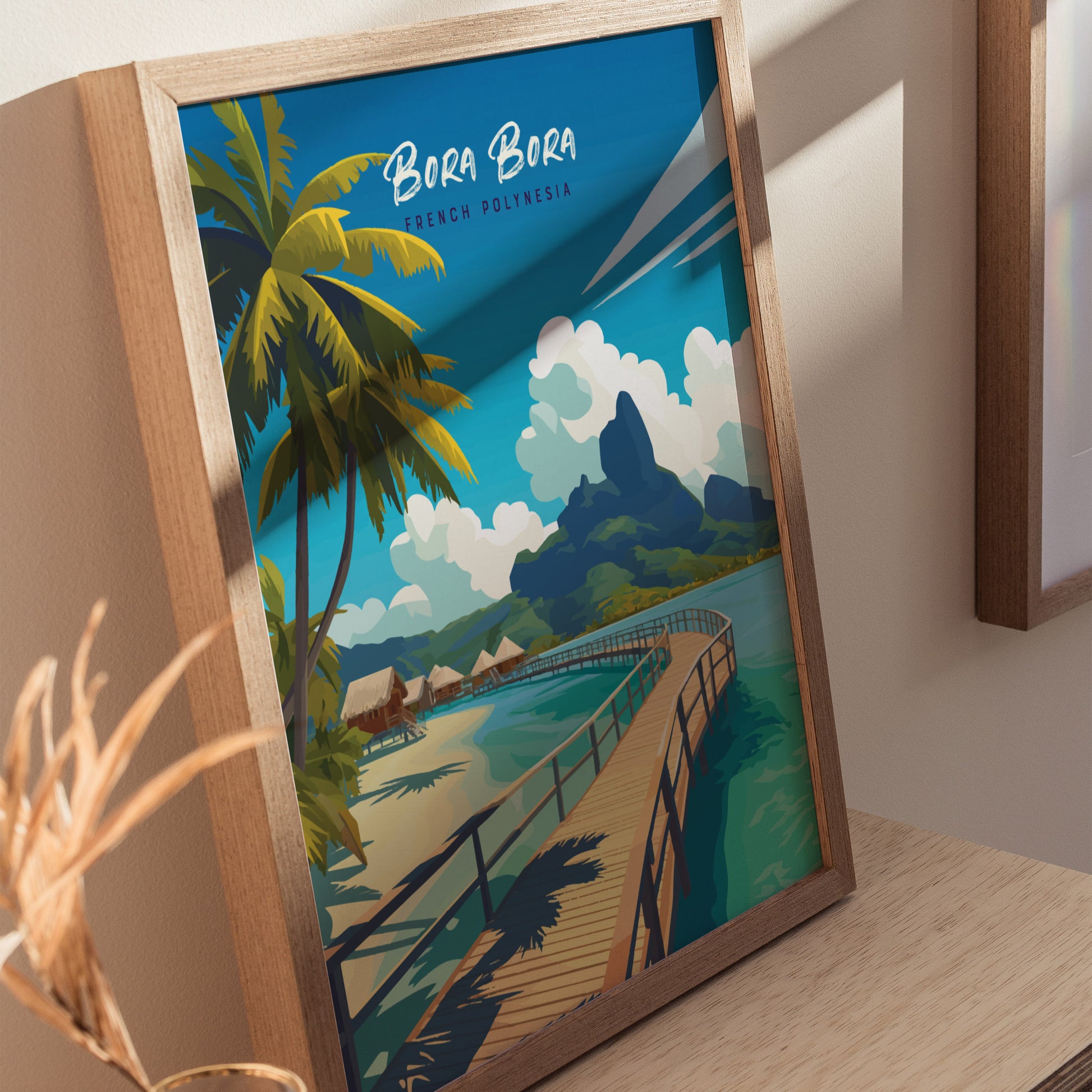 Framed artwork depicting a tropical scene with palm trees, overwater bungalows, a wooden walkway, and turquoise waters under a blue sky, labeled Bora Bora French Polynesia.