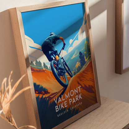 A framed poster of a mountain biker navigating a vibrant trail with the text Valmont Bike Park, Boulder, Colorado, set against a backdrop of stylized mountains and blue sky.
