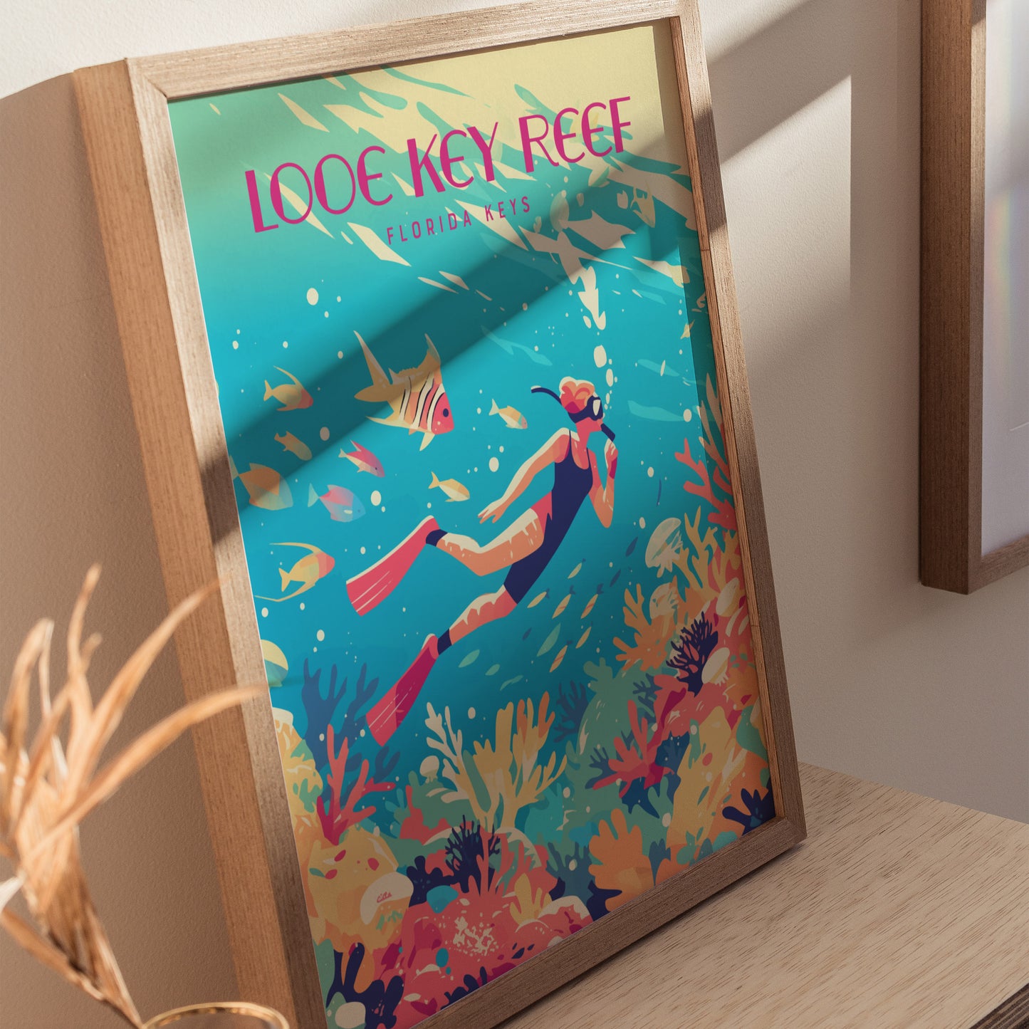 Framed poster depicting a vibrant underwater scene with a snorkeler, colorful coral, and tropical fish, titled Looe Key Reef Florida Keys, displayed on a wooden surface.