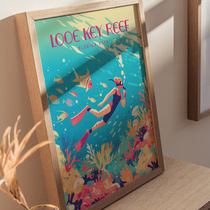 Framed poster depicting a vibrant underwater scene with a snorkeler, colorful coral, and tropical fish, titled Looe Key Reef Florida Keys, displayed on a wooden surface.