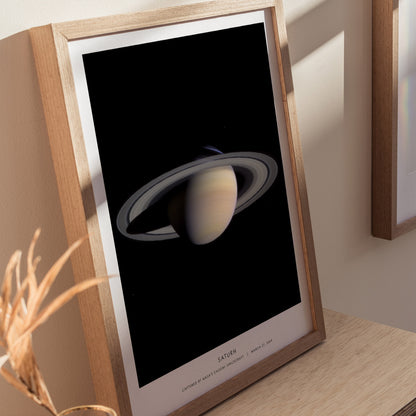 Framed poster of Saturn on a wooden surface