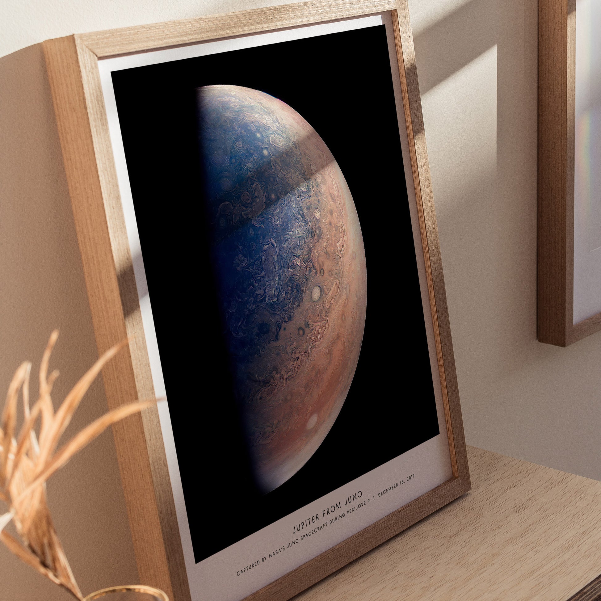 Framed print of Jupiter from Juno on a wooden surface with a neutral background