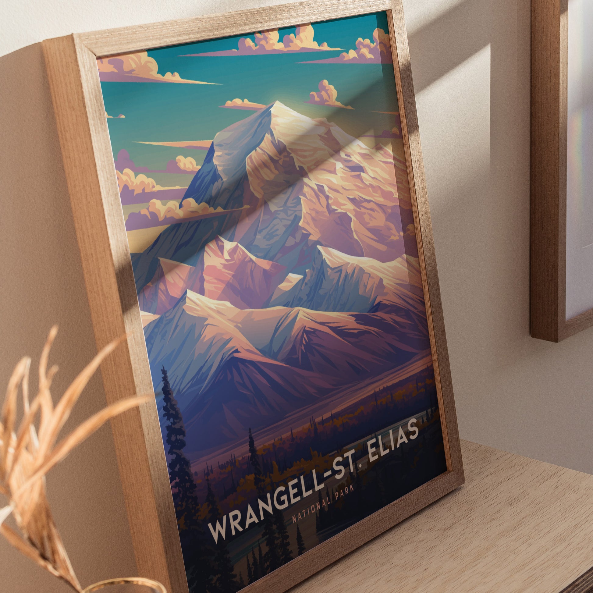 Framed art print of Wrangell-St. Elias National Park featuring colorful, stylized mountain peaks under a sky with scattered clouds, displayed on a wooden surface.