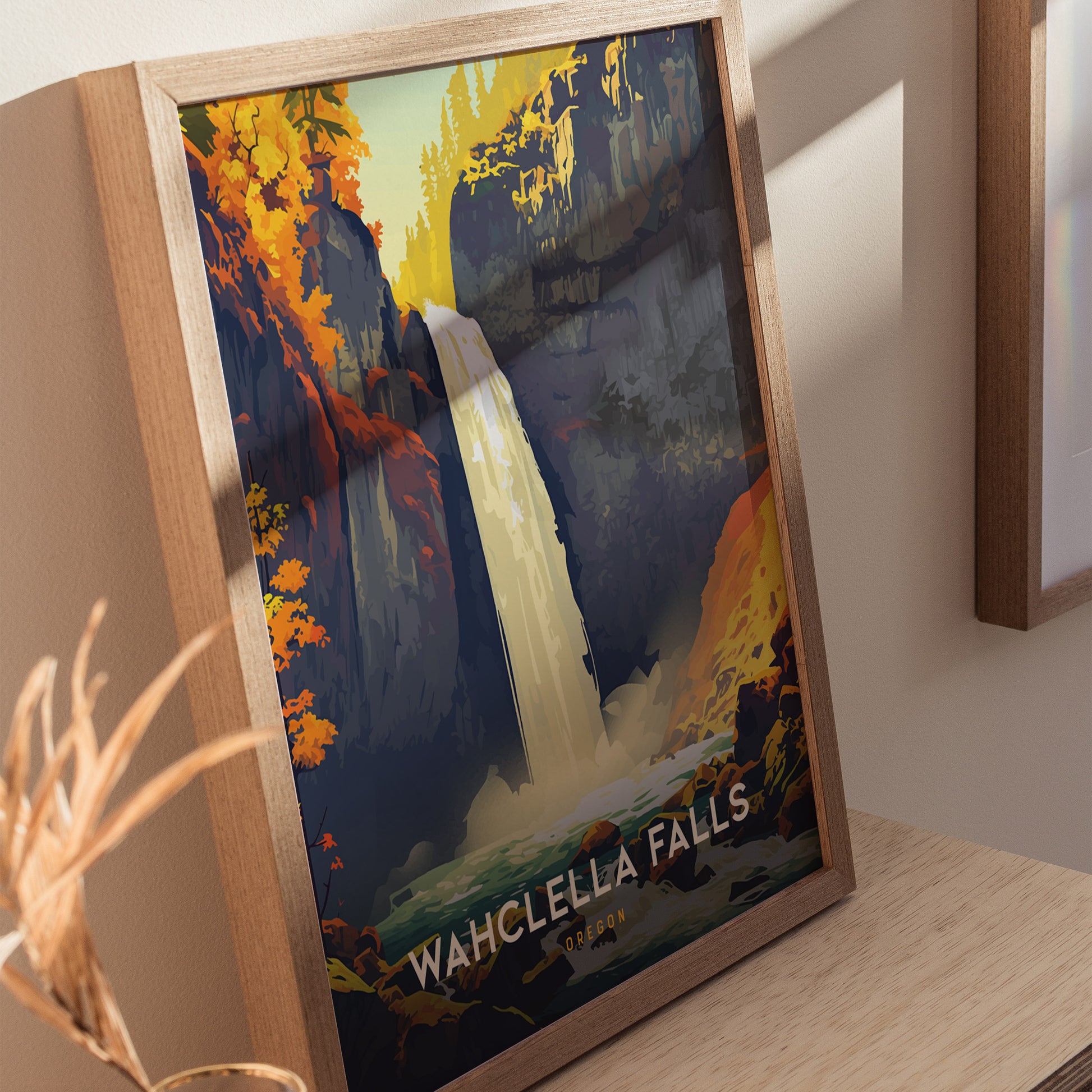 A framed poster of Wahclella Falls features a vibrant illustration of the waterfall surrounded by colorful foliage. The artwork is displayed on a wooden surface with soft natural lighting.