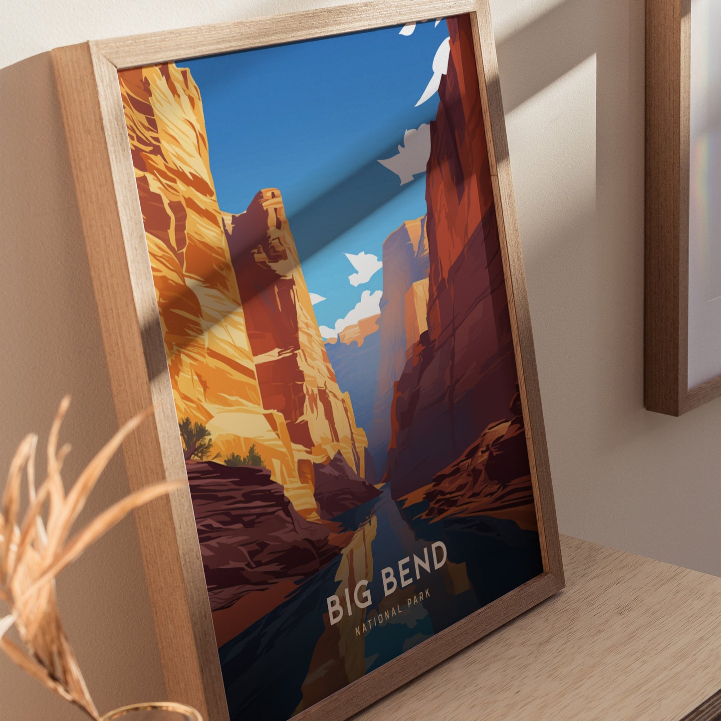 Framed poster depicting a vibrant canyon landscape with tall, colorful cliffs and a reflective river, labeled Big Bend National Park. Shadows and sunlight create a dynamic effect on the artwork.