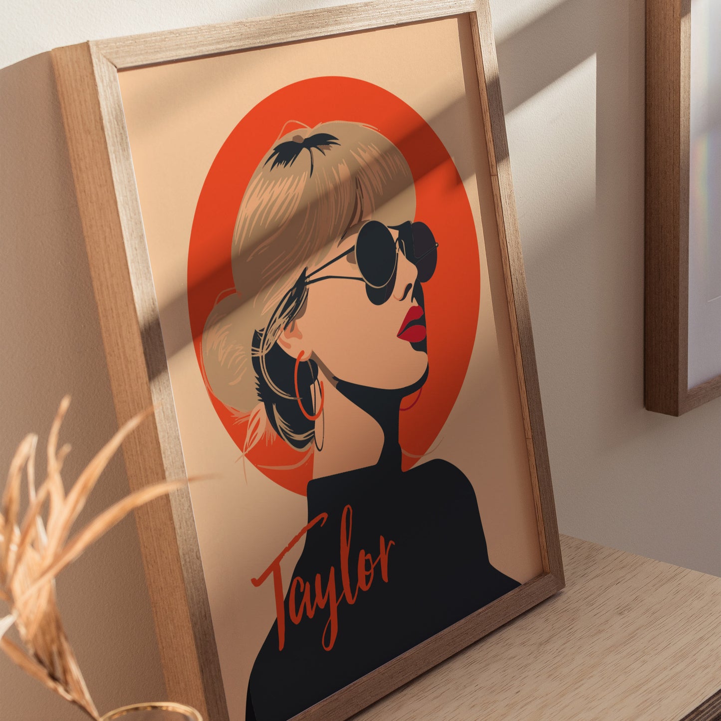 A framed minimalist art poster features a woman with sunglasses and hoop earrings, set against an orange circle, with Taylor written at the bottom.