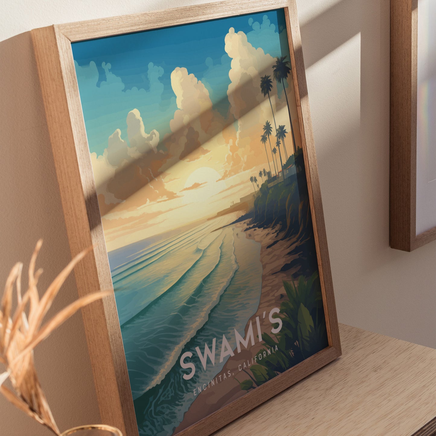 Framed artwork depicting a serene beach scene at sunset with palm trees, cliffs, and gentle waves. The text Swamis Encinitas, California is visible at the bottom.