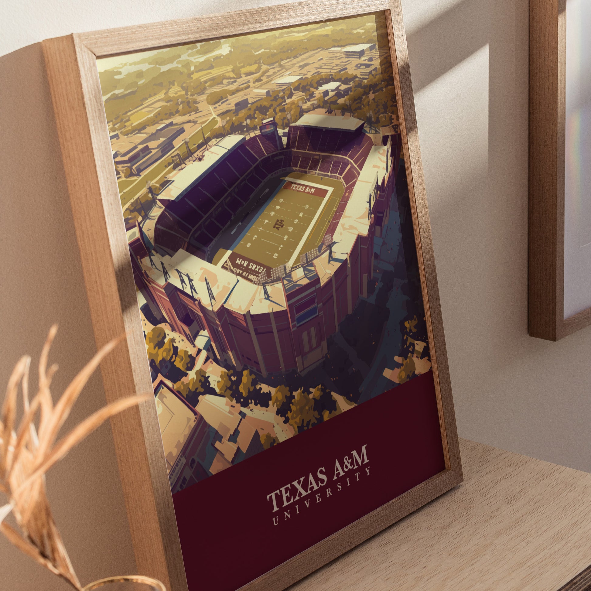 Framed poster of Kyle Field at Texas A&M University, featuring an aerial view of the stadium with surrounding landscape, displayed on a wooden surface.