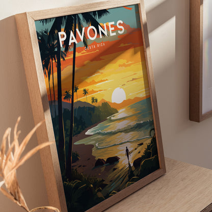 Framed poster featuring a vibrant sunset over a tropical beach with palm trees and waves, titled Pavones Costa Rica. A figure walks along the shoreline, adding a serene touch.