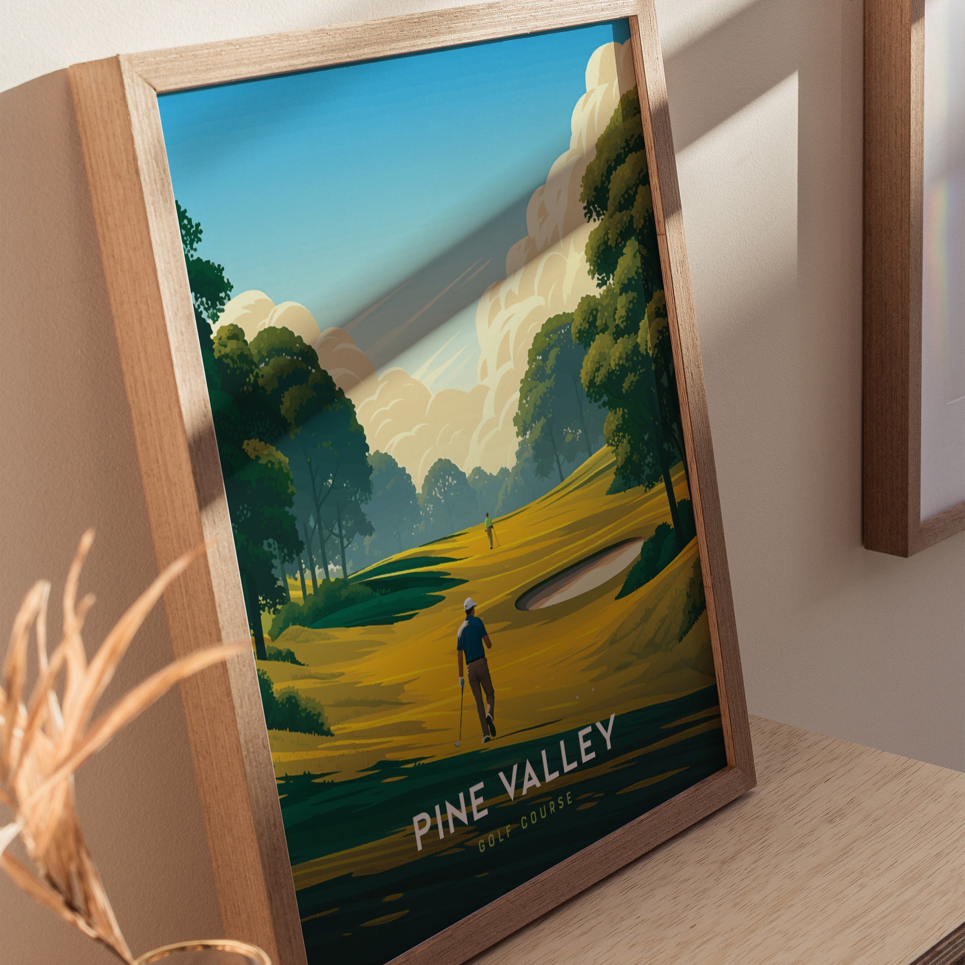 A framed Pine Valley Golf Course poster features a stylized illustration of a golfer on lush fairways surrounded by trees under a blue sky with clouds.