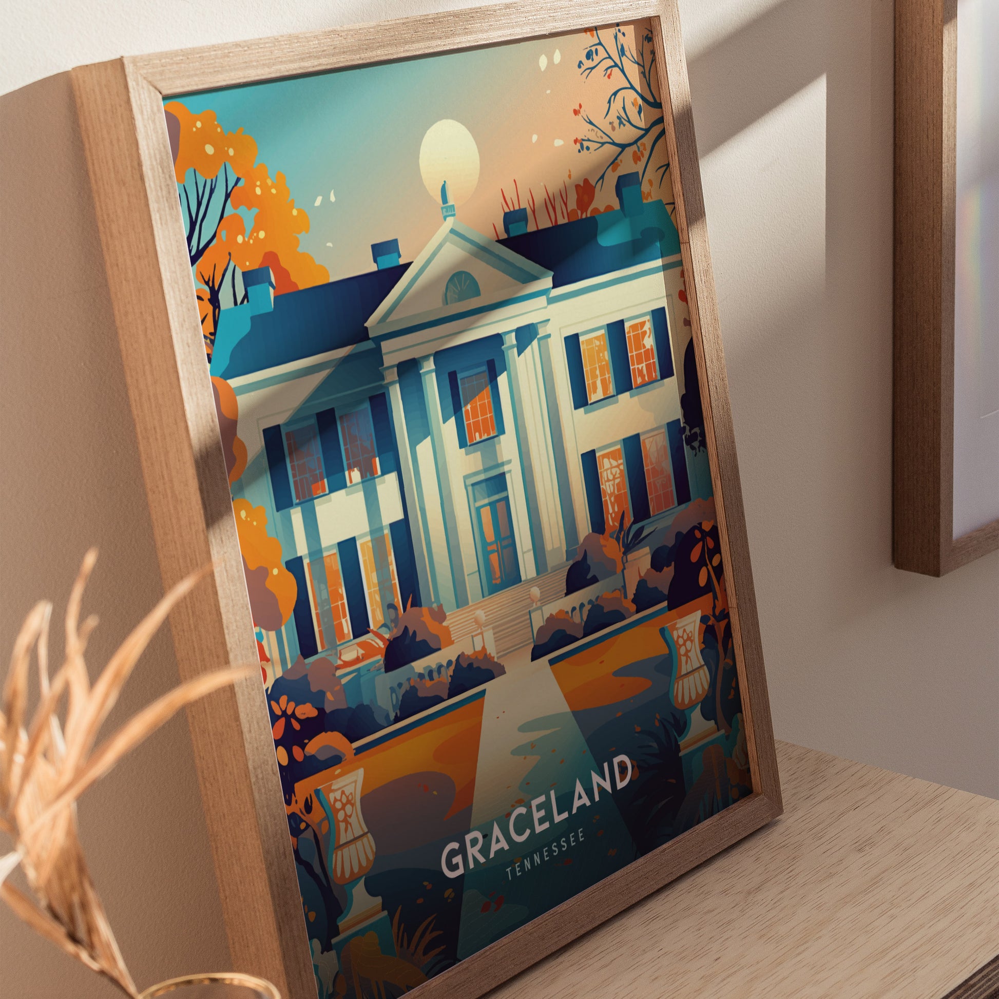 Framed artwork depicting the iconic Graceland mansion against a sunset sky, surrounded by autumn trees. The vibrant illustration highlights the classic architecture and reads Graceland, Tennessee at the bottom.