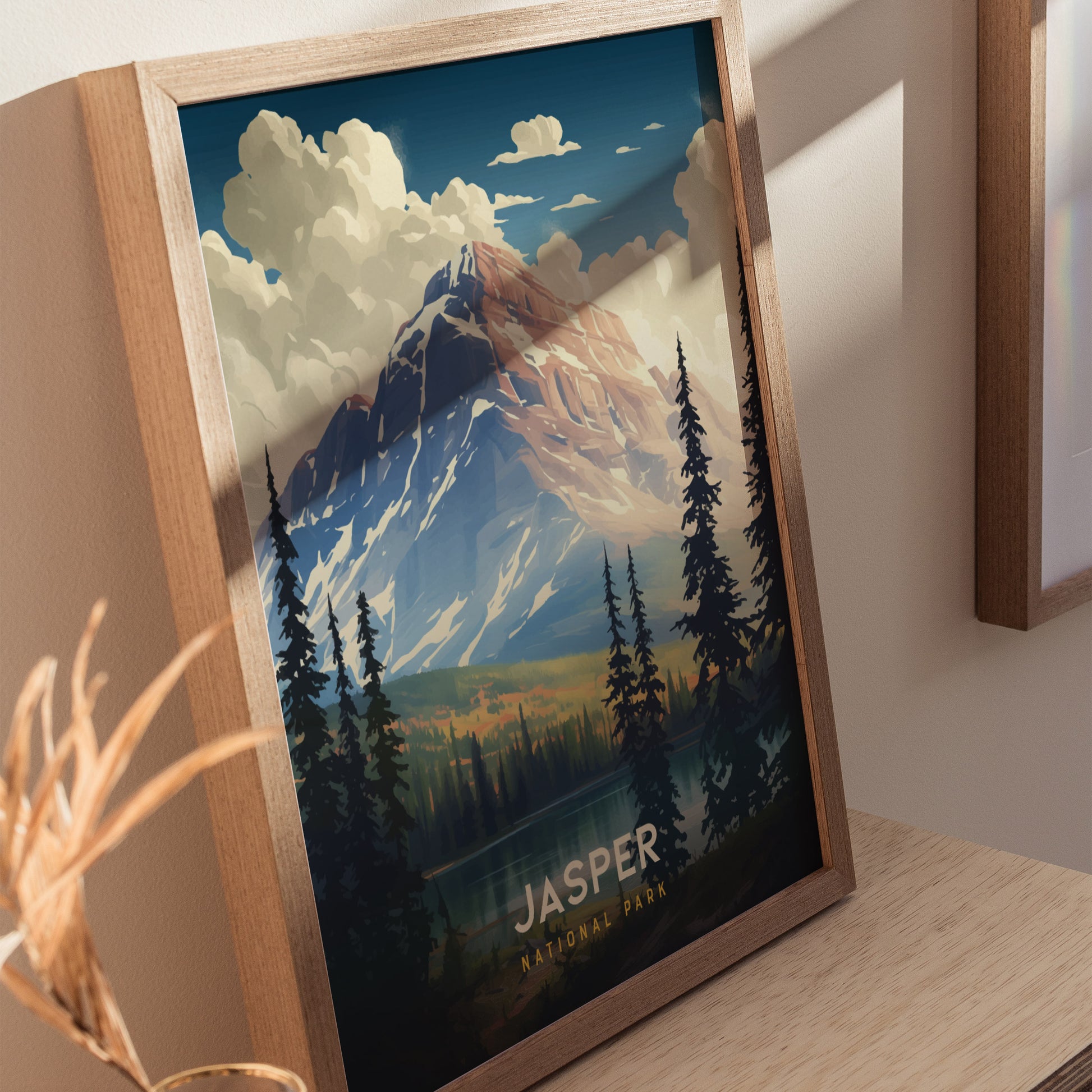 Framed poster of Jasper National Park featuring a mountain landscape with pine trees, clouds, and a serene lake, set on a wooden shelf.