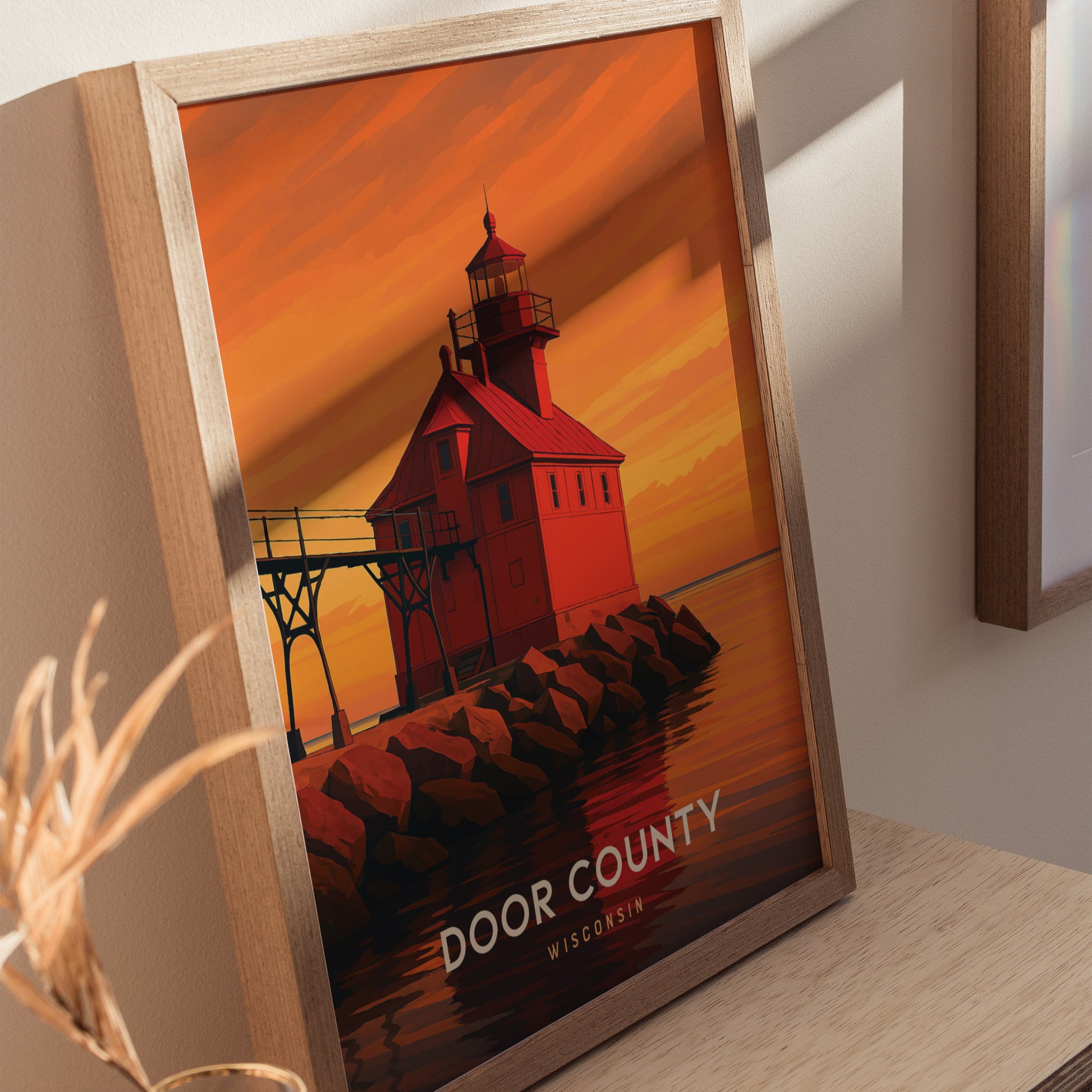 A framed art print featuring a vibrant illustration of a red lighthouse at sunset, set against an orange sky with reflections on the water. The text DOOR COUNTY WISCONSIN is displayed prominently at the bottom of the image.
