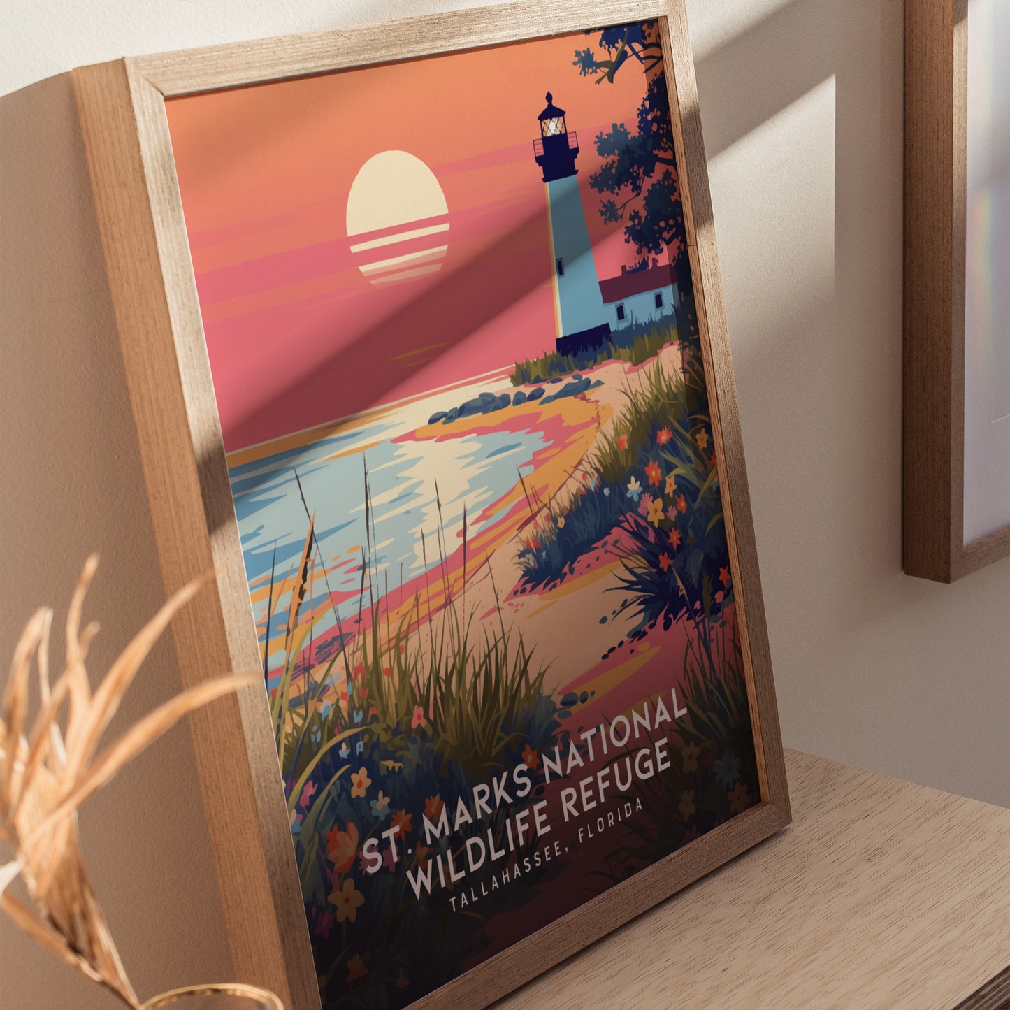Framed poster of St. Marks National Wildlife Refuge features a lighthouse at sunset with vibrant wildflowers and coastal marshes, styled in a vintage travel poster design.