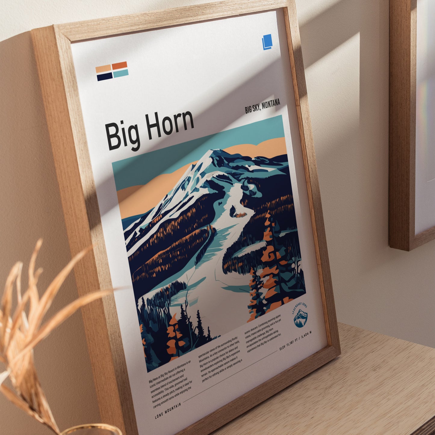 Framed poster of Big Horn ski run in Big Sky, Montana, featuring a stylized mountain landscape with snowy slopes and trees, placed on a wooden surface.
